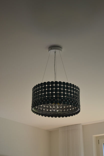 Kronleuchter klein mit grünen Nespresso-Kapseln hängt an Stahlseilen unter der Decke